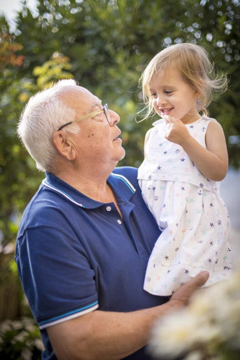 An elderly man lovingly holding his granddaughter, sharing a tender moment