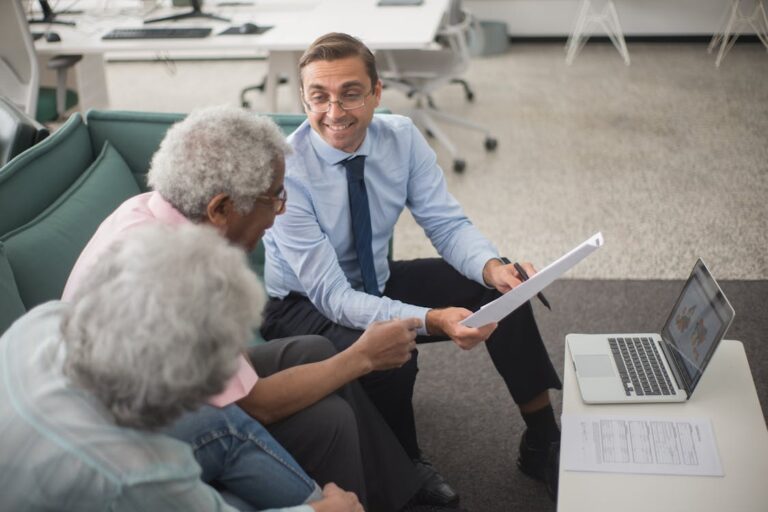 Elderly couple discussing documents with a Medicare agent in Dallas, TX.