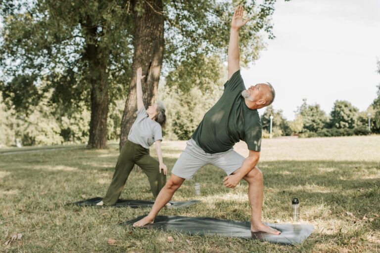 An elderly couple exercising outdoors in a park, enjoying physical activity to manage arthritis symptoms.