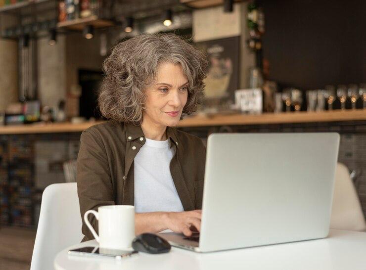 A woman sitting in a café researching Medicare Advantage plans on her laptop.
