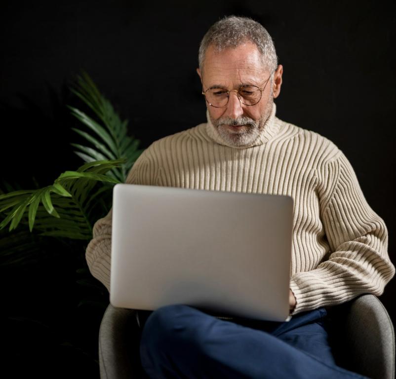 An elderly man thoughtfully reviewing the WISeR model information on a laptop at home.