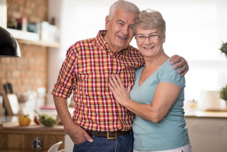 An elderly couple posing for a photo at home.