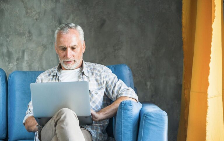 A senior citizen reviewing Medicare plan on a laptop during the Annual Open Enrollment Period.