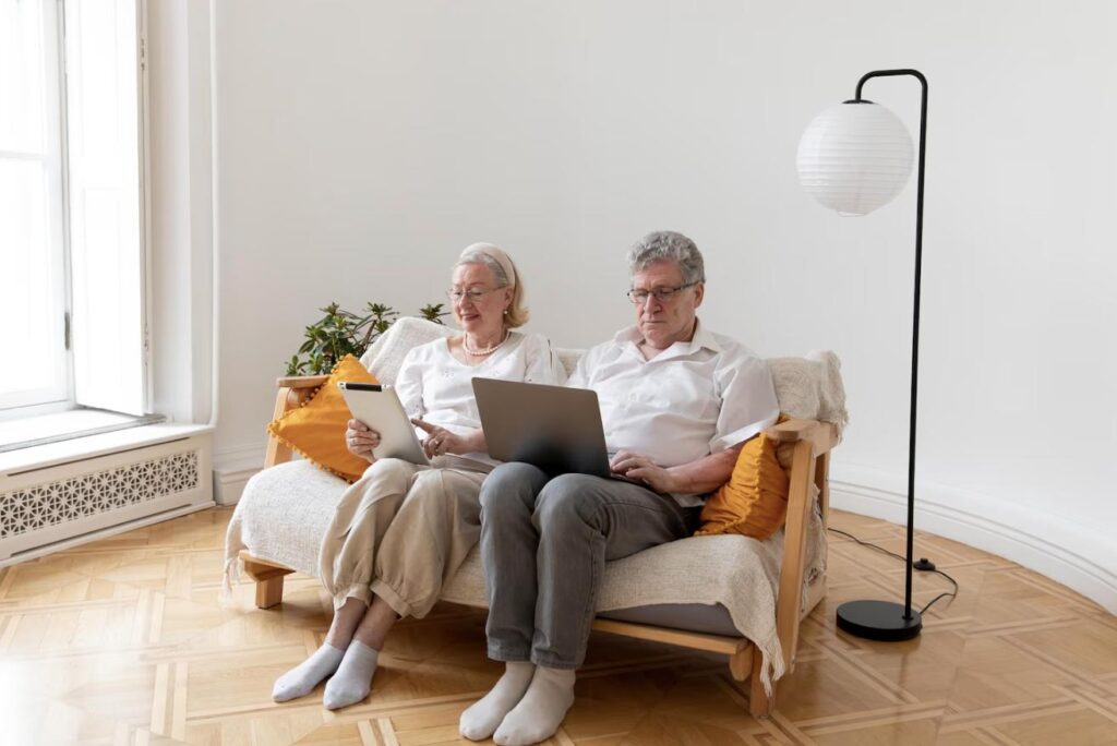 A senior couple using a laptop together while sitting on a couch.