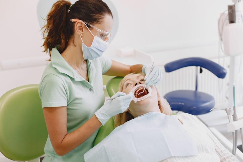 a dentist wearing a mask, treating an older woman's teeth