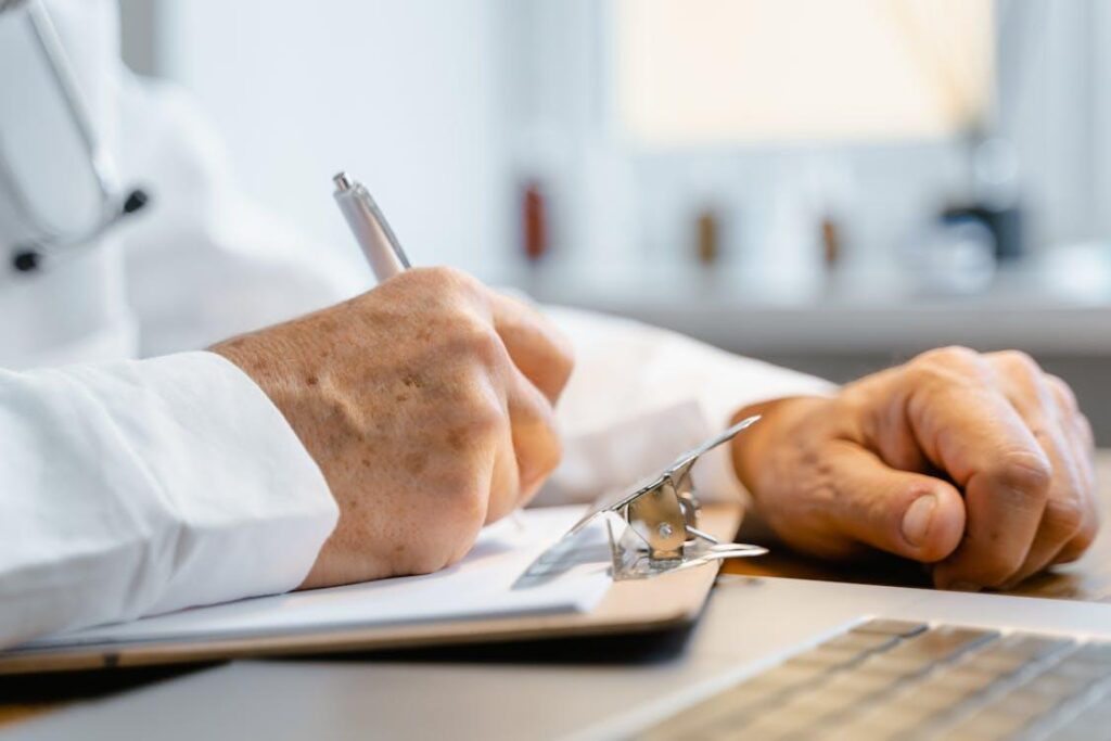 a doctor wearing a stethoscope writing on a clipboard with a pen