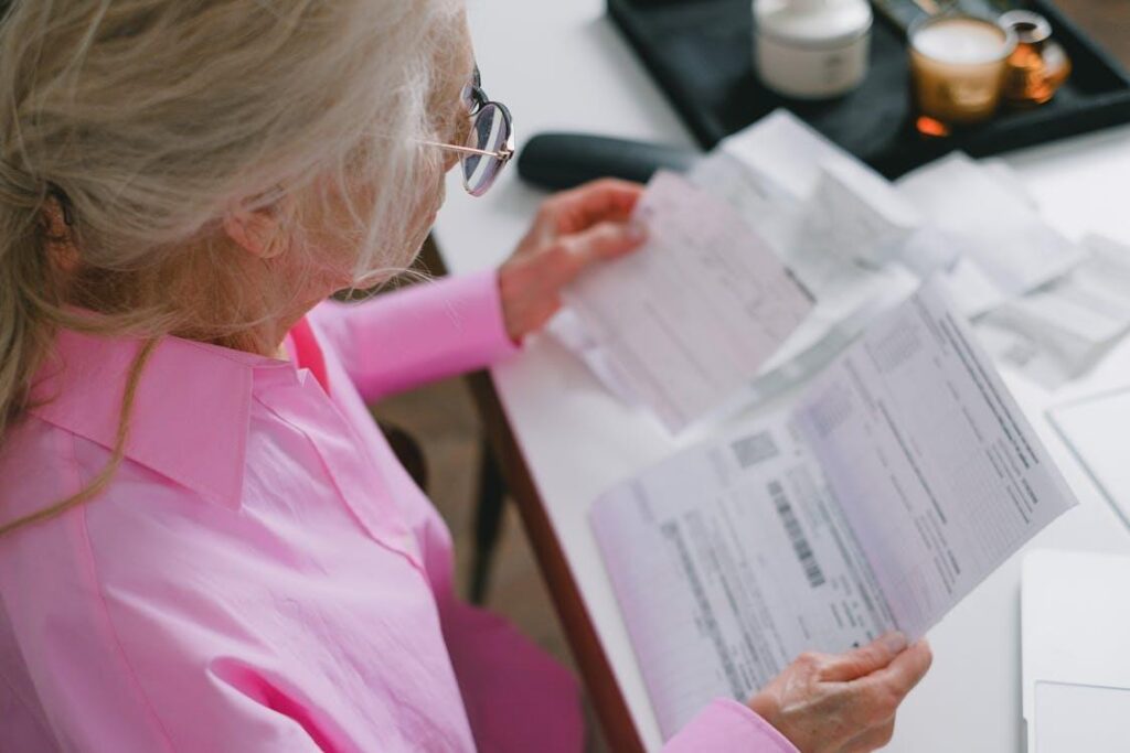 an elderly woman wearing a pink shirt, reading a document