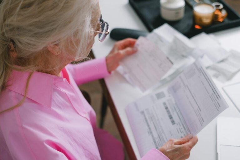 an elderly woman wearing a pink shirt, reading a document