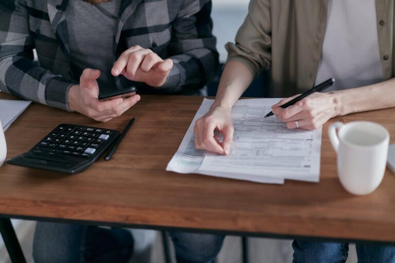 close-up of two people sitting together doing paperwork and computing taxes