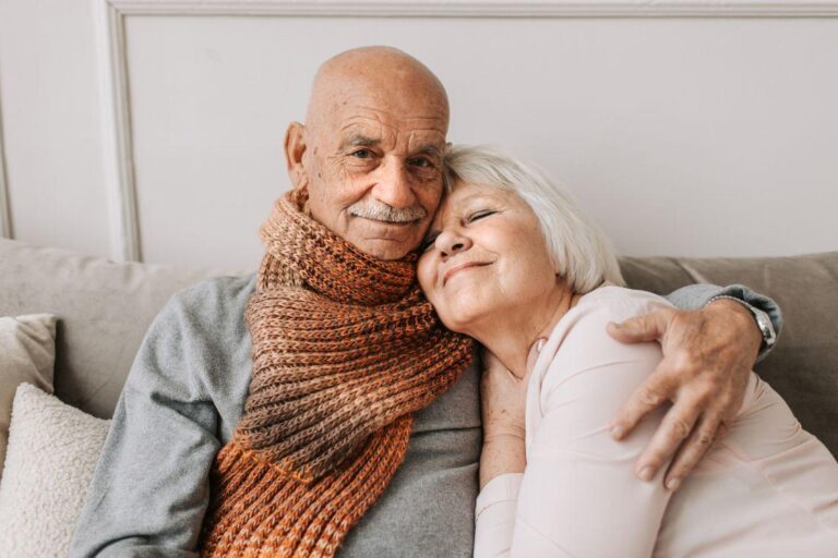 An older couple hugging on a couch.