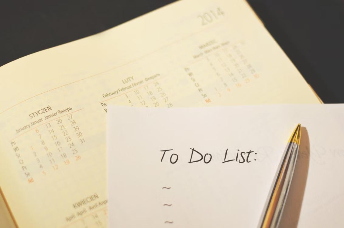 A calendar and to-do list checklist sit on a desk with a pen.