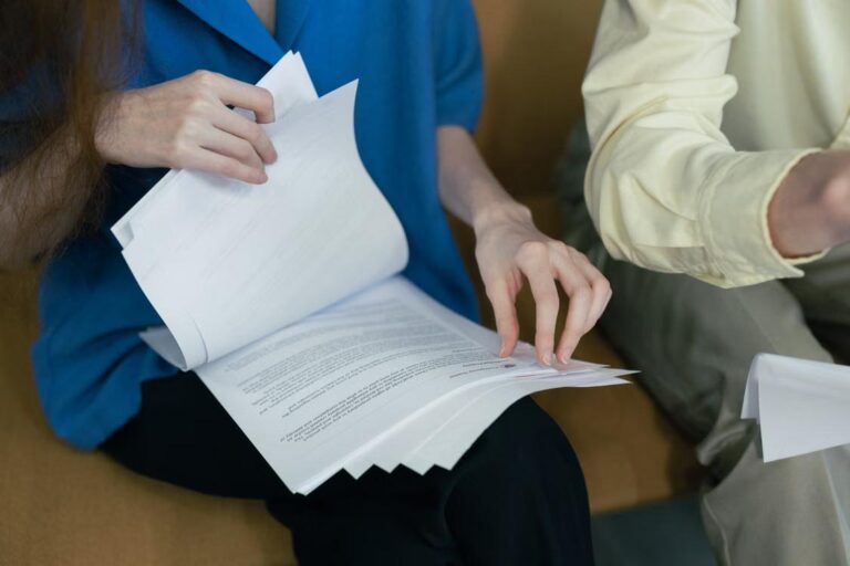People in professional attire review documents together while seated.