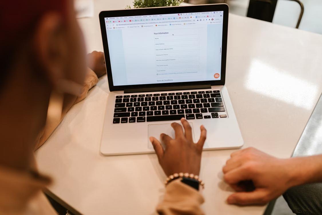 Two people fill out an online form together using a laptop.