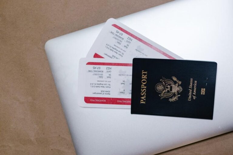 A passport and boarding passes rest on top of a laptop.