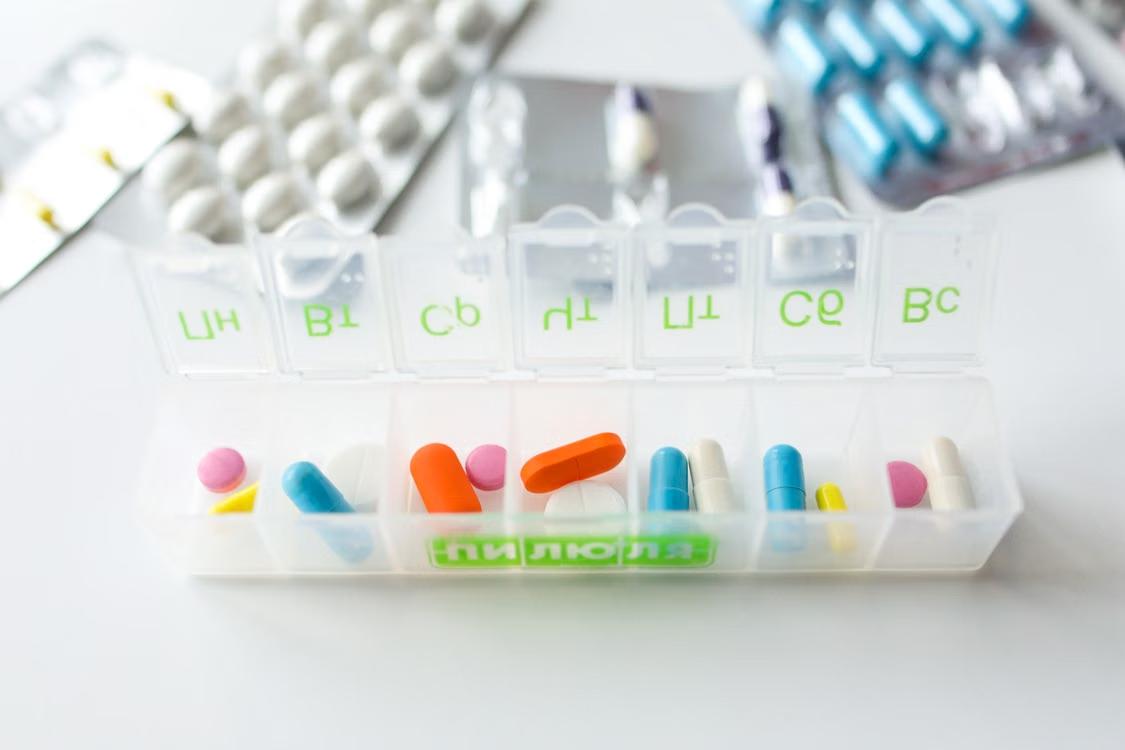 Colorful pills organized in a labeled weekly pill organizer.